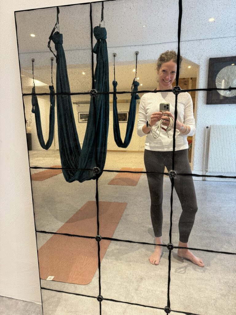 Salle de yoga avec les hamacs de yoga aérien installés et les tapis prêts pour la séance